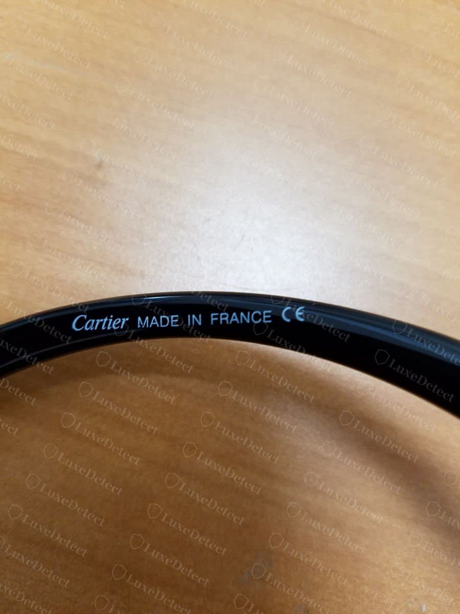 Innenseite eines gefälschten Cartier-Bügels an einem schwarzen Acetat-Arm: „Cartier MADE IN FRANCE“ mit CE-Zeichen in hellblauer Groteskschrift, ohne „PARIS“ und ohne Größenangabe in der Zeile