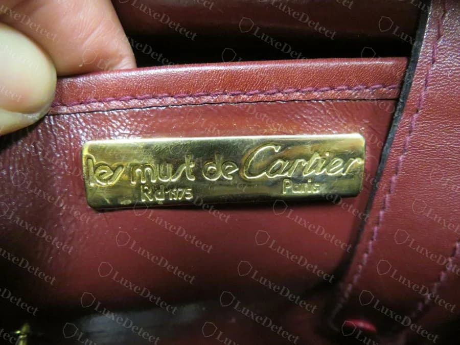 Una borsa Must de Cartier più vecchia originale con una targhetta interna dorata con la scritta les must de Cartier, Paris, e un marchio Rd 1975