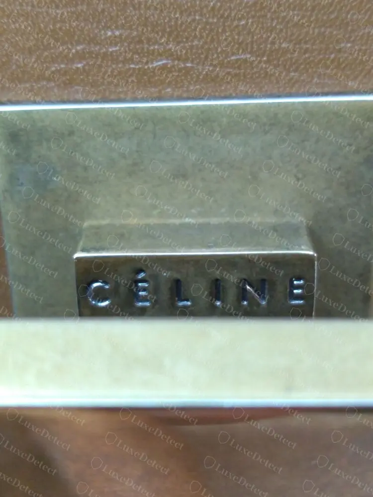 Lingueta de fecho falsificada. A gravação CÉLINE é nítida e de espaçamento uniforme, como em quase todas as falsificações que analisamos. Um fecho de boa aparência não libera a bolsa.
