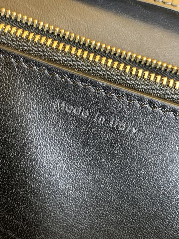 Authentic "Made in Italy" stamp on black lambskin lining. The italic letters are light and shallow and fade into the grain.