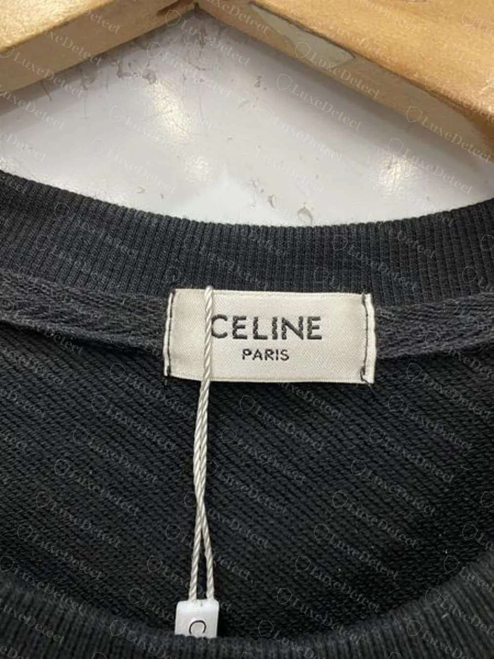 Sudadera Celine falsificada: etiqueta de cuello tejida CELINE PARIS, sin acento, sobre una percha