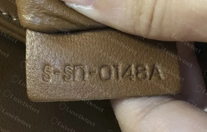 Counterfeit Teen Triomphe serial tag: S-Sn-0148A, with a lowercase-looking n, misshapen S characters, and a fifth character tacked on after the digits.