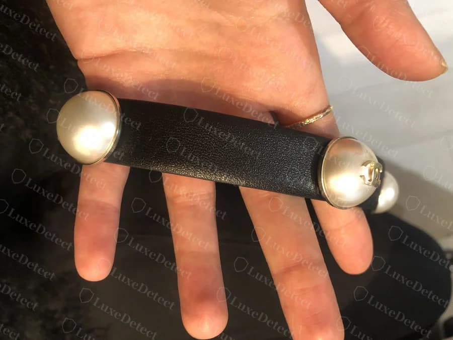 Genuine Chanel pearl-embellished belt buckle, showing the two faux-pearl end caps and the small CC medallion set into the leather bridge between them