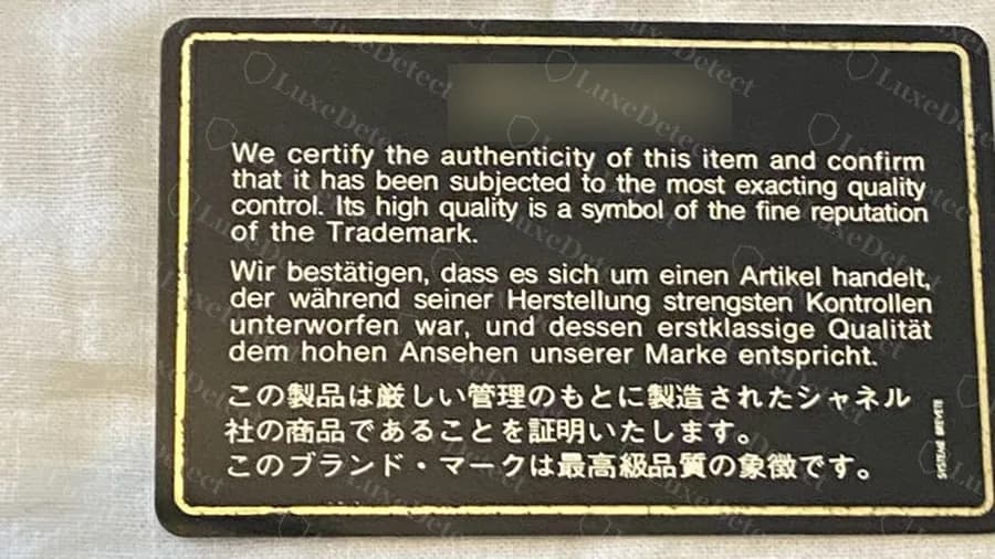Genuine black Chanel authenticity card with the certification text in English, German and Japanese and a printed number at the top (number blurred)