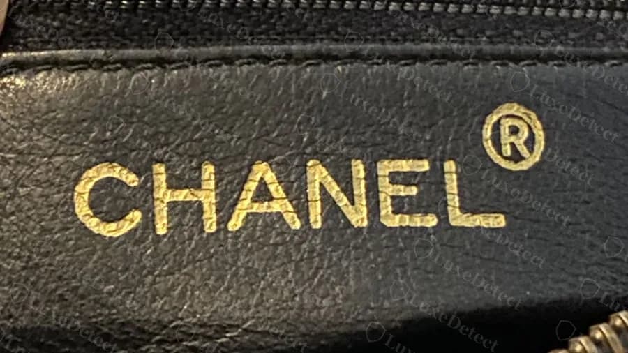 Sello CHANEL dorado original con la marca registrada sobre el forro de piel negra de un Camera Bag vintage
