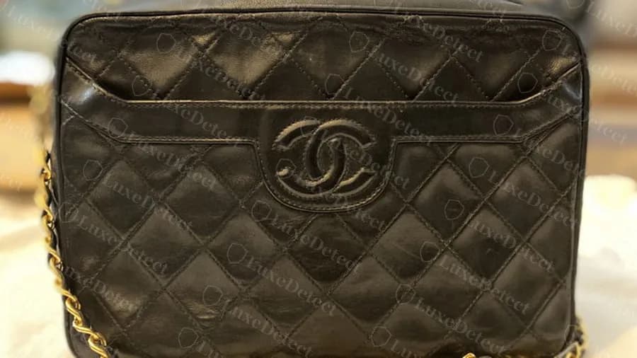 Genuine vintage Chanel Camera Bag in black quilted lambskin: zip top, front pocket flap with a stitched CC and a gold leather-woven chain