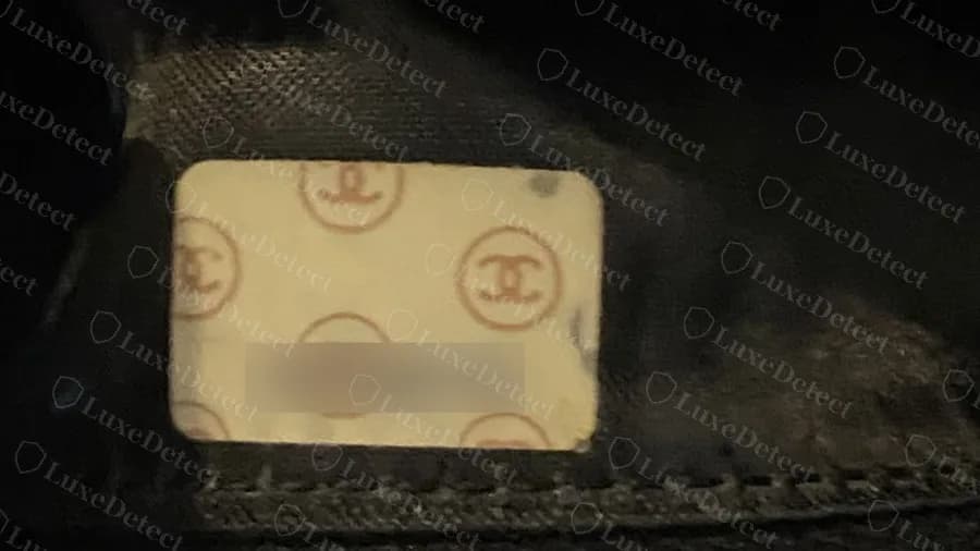 Genuine interior serial sticker on a vintage Chanel Camera Bag: cream label with a pattern of small CCs and a printed number (number blurred)