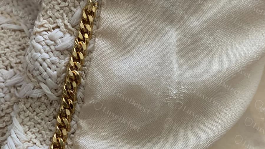 Genuine gold chain sewn along the inside front edge of a cream tweed jacket with silk lining