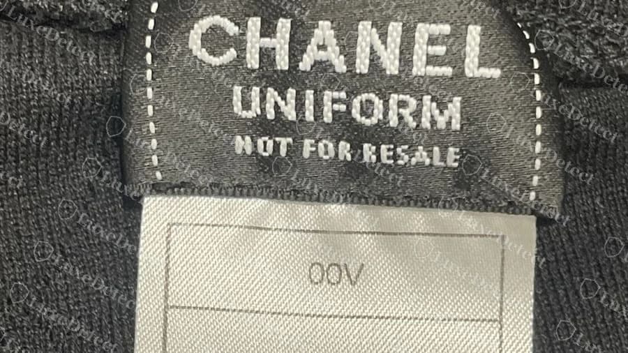 Etiqueta del cuello Chanel Uniform original que dice CHANEL, UNIFORM, NOT FOR RESALE, encima de una etiqueta gris lisa con un recuadro de código