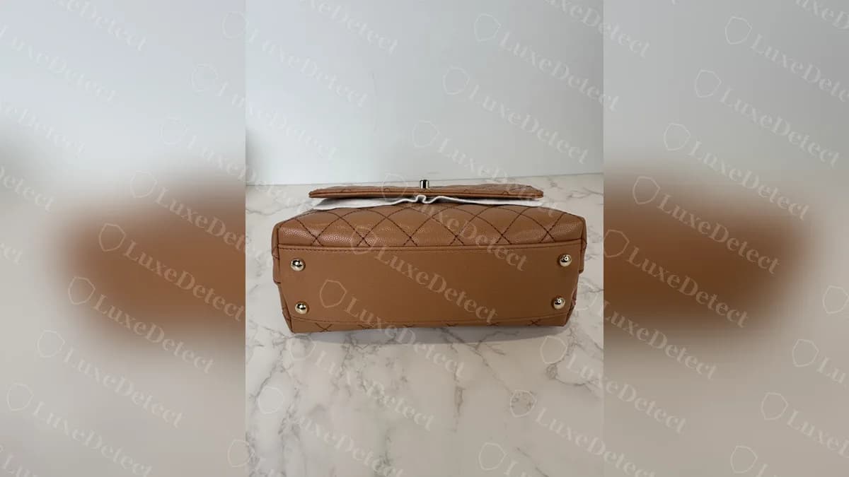 Base of a genuine Coco Handle with round metal feet and quilting that continues around the bottom of the bag