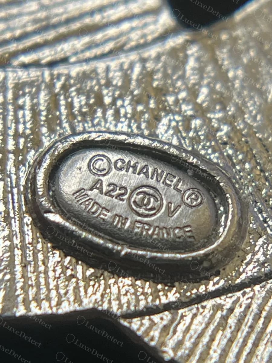 Genuine Chanel brooch plaque, "©CHANEL® A22 V MADE IN FRANCE" in fine, evenly spaced lettering with a clear gap between each word