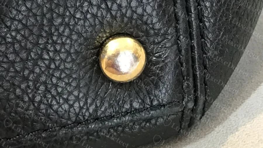 Genuine Executive Tote base stud: a domed gold metal foot set in the corner seam at the bottom of the bag