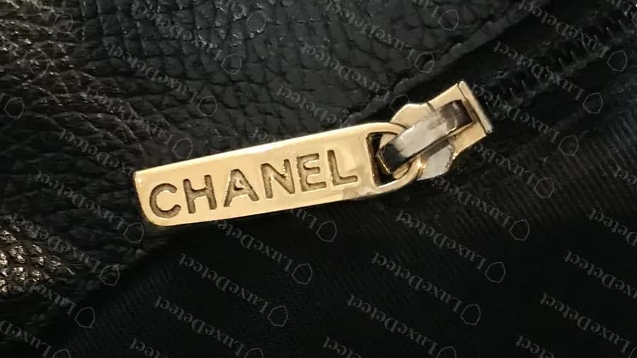 Genuine Executive Tote zip pull: a flat gold bar engraved CHANEL, photographed upside down against the black lining