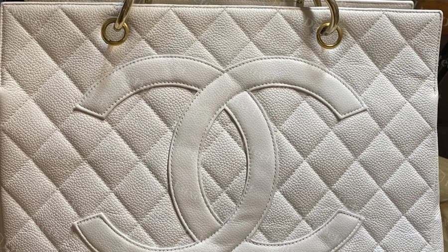 Genuine white caviar Grand Shopping Tote with gold hardware: a large stitched-in CC over diamond quilting and gold-ring grommets at the top corners