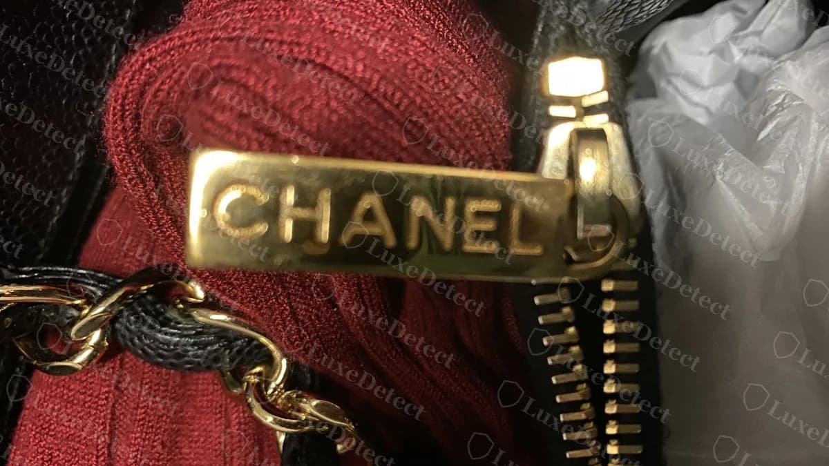 Genuine black GST zip pull in gold: a flat bar with CHANEL engraved in capitals, against the interior zip