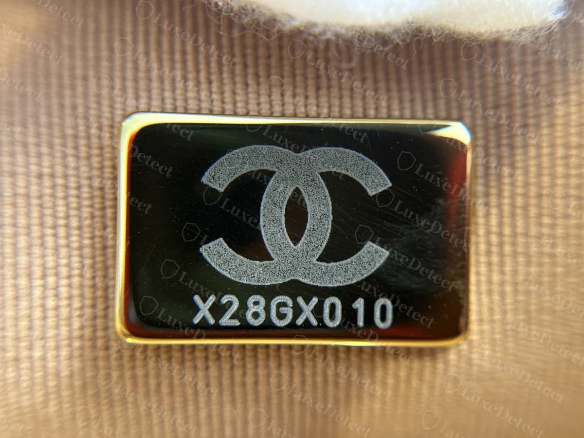 Genuine gold-tone plate on the beige lining of a recent Chanel 19: the CC logo above the 8-character code X28GX010