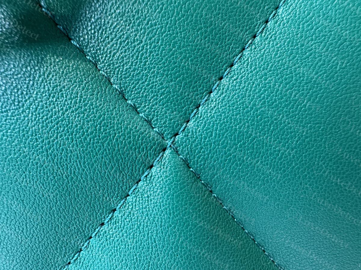 Primer plano del acolchado de un Chanel 19 original de piel de cordero verde: rombos grandes y suaves con las costuras aplanadas entre ellos y un acabado liso y brillante