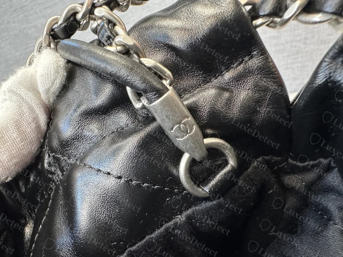Genuine silver-tone clasp on a black Chanel 22: an aged silver hook engraved with the CC logo, with a leather-covered end