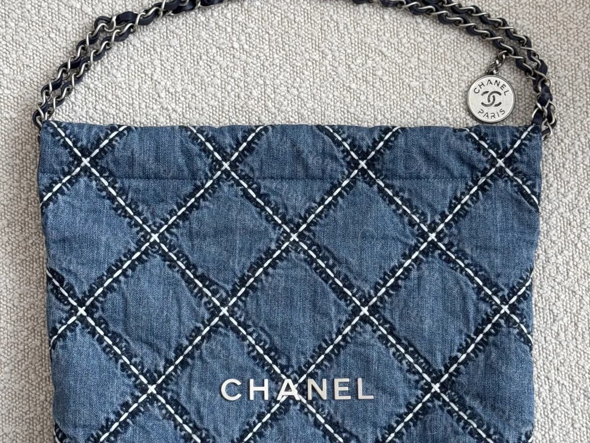 Genuine Chanel 22 in blue stitched denim: contrast stitching along the quilted diamonds, the CHANEL letters in silver-tone and a chain with a medallion
