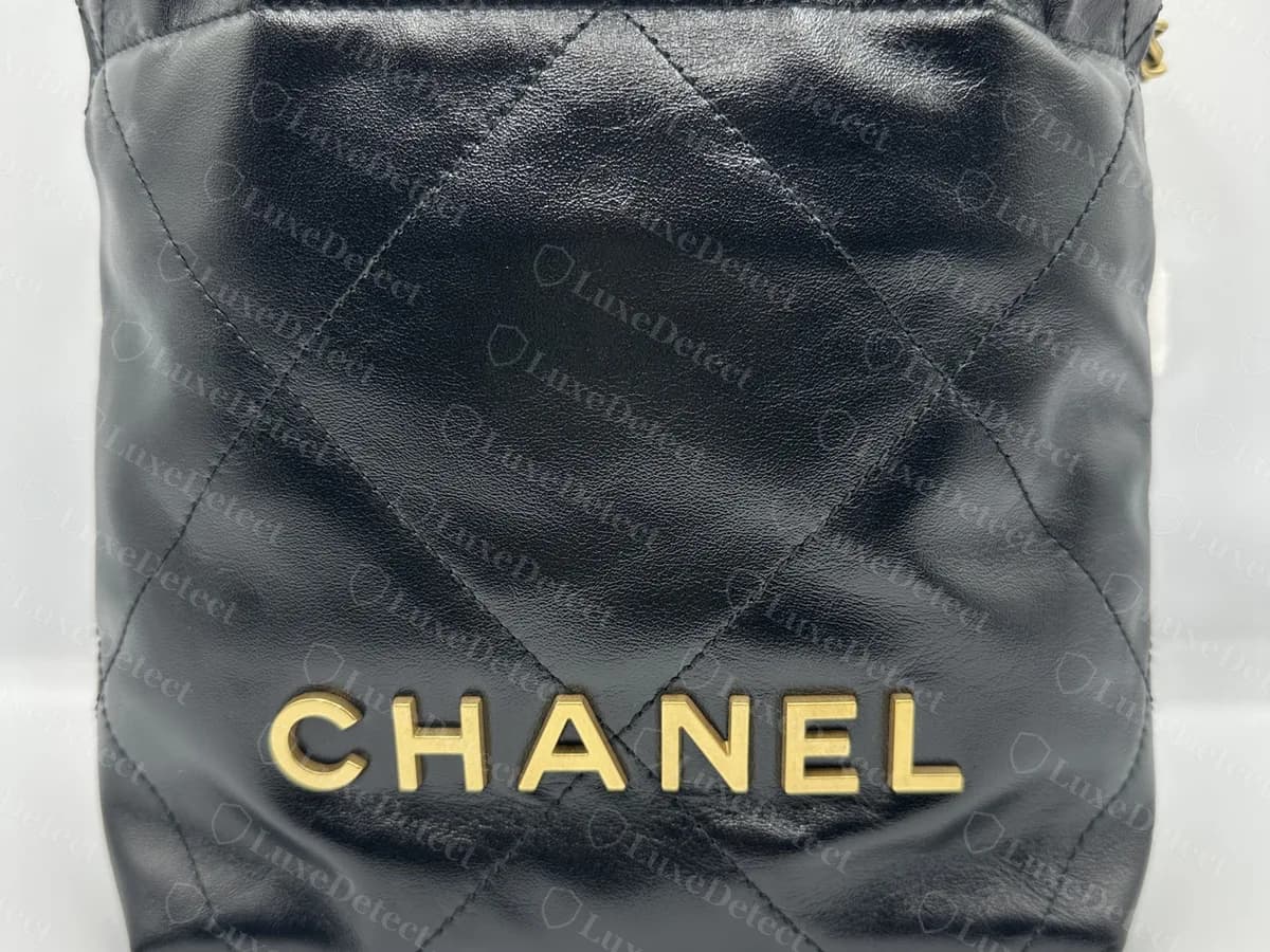 Genuine Chanel 22 Mini in black shiny calfskin from the front: a slouchy quilted body gathered at the top, with gold-tone CHANEL letters across the lower front
