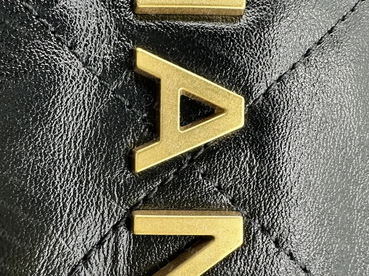Genuine Chanel 22 close-up: a raised, matte gold-tone metal letter sitting on the quilted calfskin, with clean edges