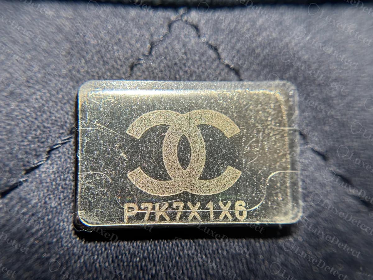 Genuine silver-tone serial plaque on a denim Chanel 22: the CC logo above an eight-character code, with a thin transparent layer over the face and notched corners