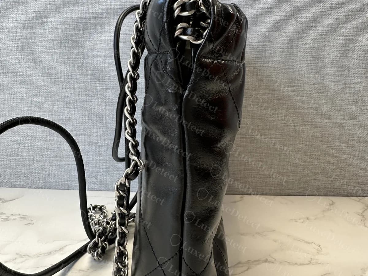 Genuine Chanel 22 Mini from the side: a slim quilted body with the chain and leather strap hanging from the top