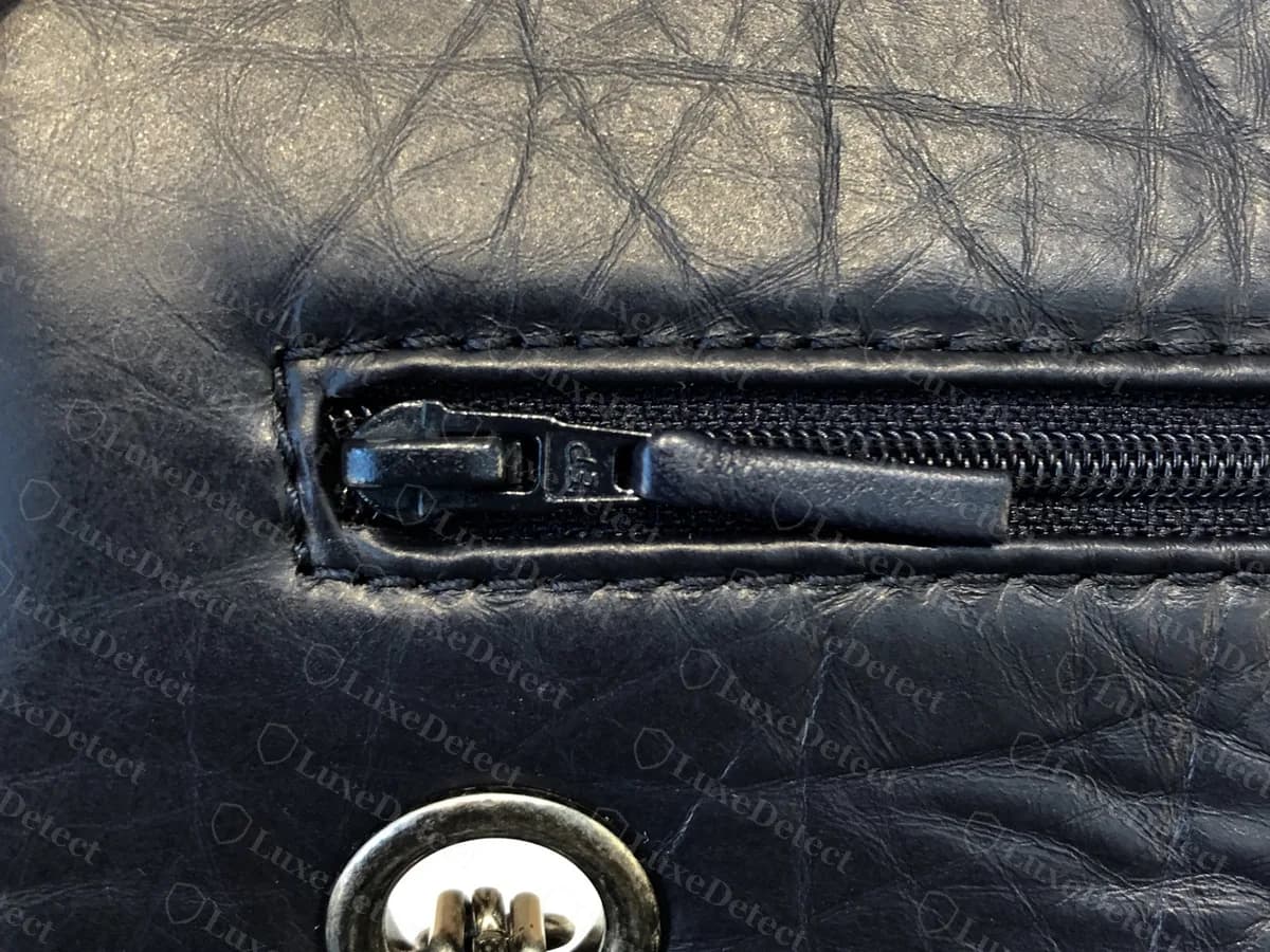 Reissue azul marino original visto por detrás: un bolsillo exterior con cierre sobre piel arrugada y veteada, con un aro plateado y el cierre abajo