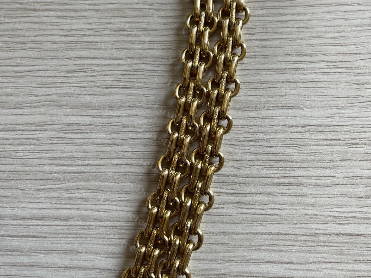 Catena autentica a più fili tutta in metallo, in oro anticato, fotografata su una superficie di legno, senza pelle intrecciata
