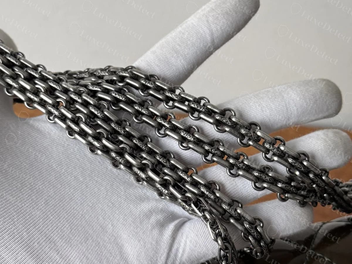 Chaîne multibrin métallique foncée authentique d’une commande de 2.55, posée sur une main gantée