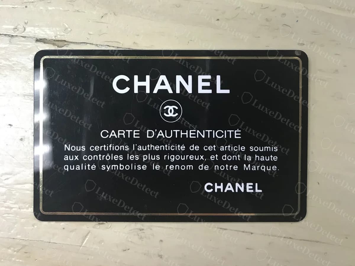 Frente de una tarjeta de autenticidad original de Chanel: "CHANEL", una CC dentro de un círculo y las palabras "CARTE D'AUTHENTICITE" con una breve certificación en francés