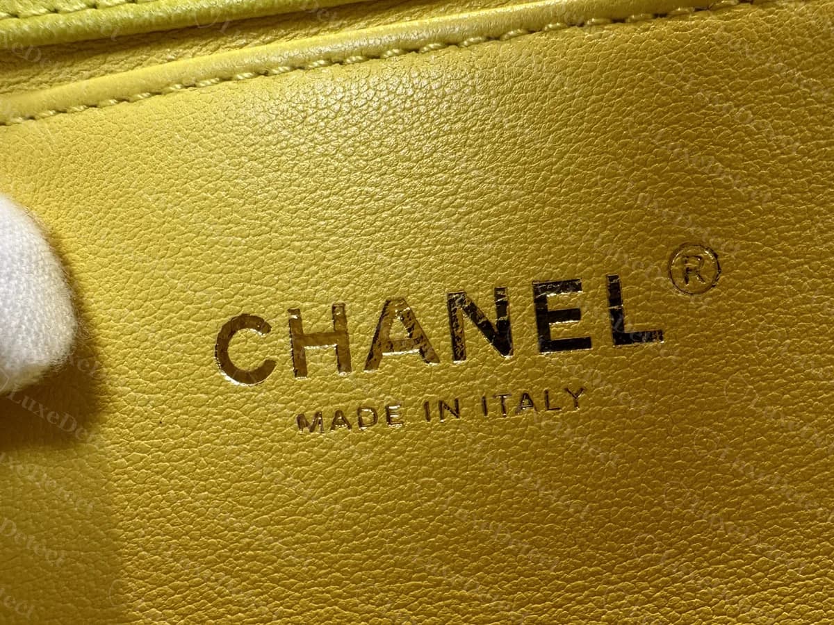 Intérieur d'un Boy Chevron jaune authentique : CHANEL en capitales avec une marque déposée au-dessus de MADE IN ITALY en petites capitales, estampillé dans la doublure en cuir lisse