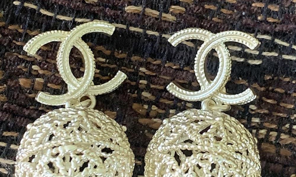 Pendiente CC de Chanel falso: las C con una textura genérica gruesa de estrías en lugar del motivo grabado, con extremos más redondeados y blandos que el corte original