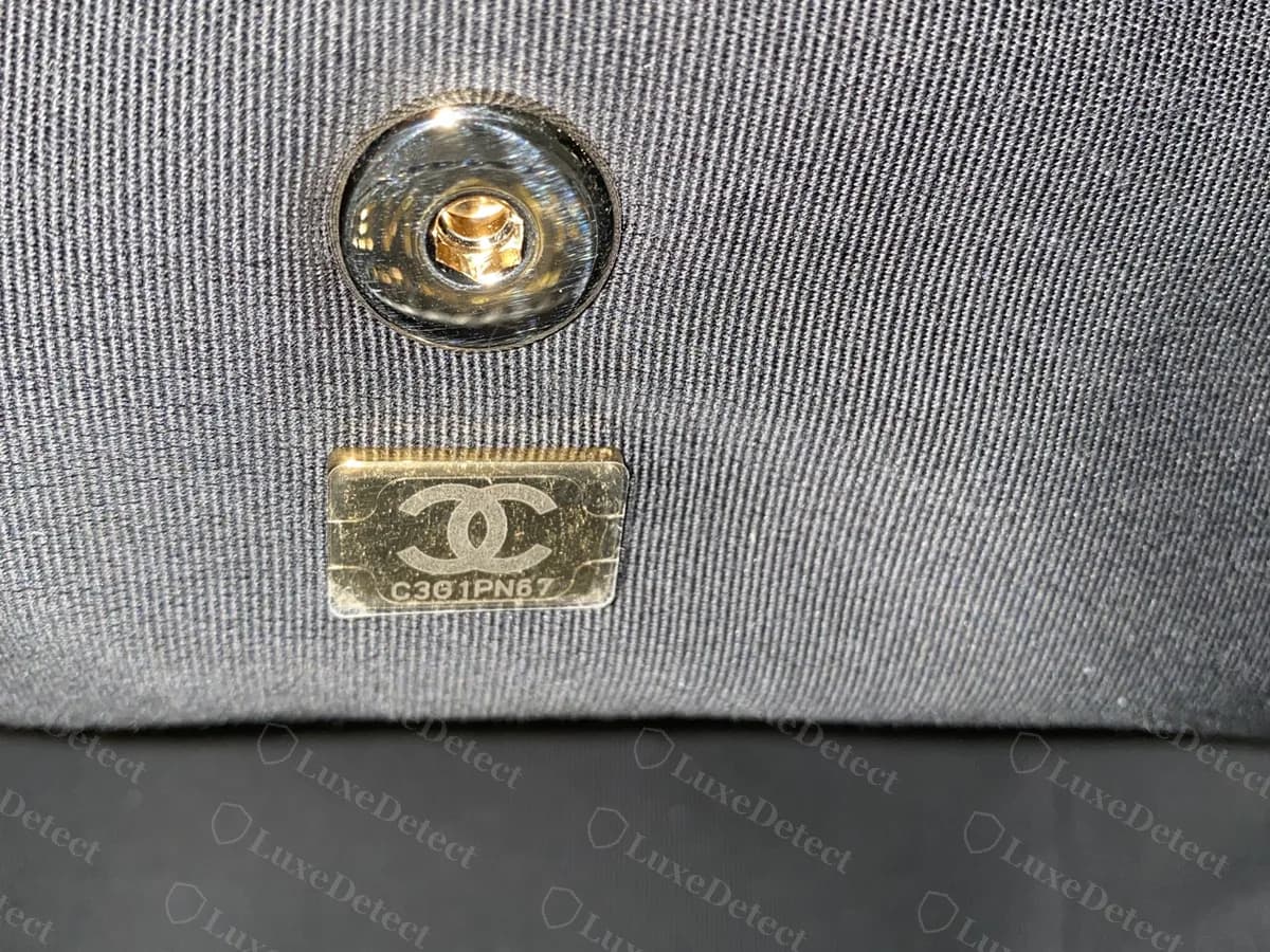 Targhetta con microchip Chanel originale nella fodera della borsa: una piccola targhetta dorata dal contorno a gradini, con logo CC e codice, sotto il bottone automatico interno