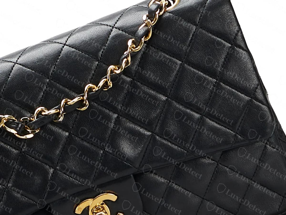 Echte schwarze Lammleder-Classic-Flap: gleichmäßige Rautensteppung auf Klappe und Korpus und eine goldfarbene Kette mit schwarzem Leder, das durch die Glieder gezogen ist