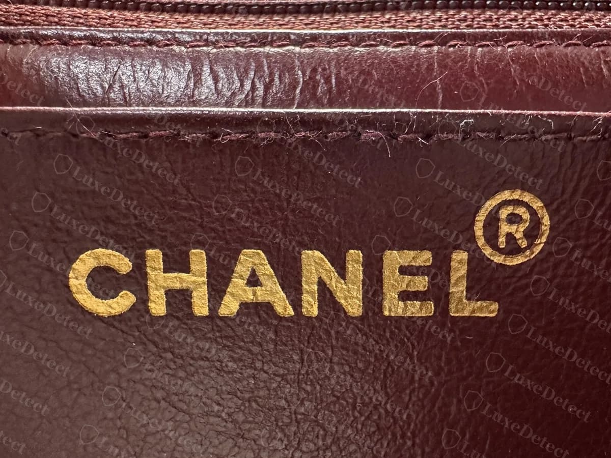 Jumbo de solapa simple vintage original: un sello CHANEL dorado grande con el símbolo de marca registrada, sobre forro de piel burdeos