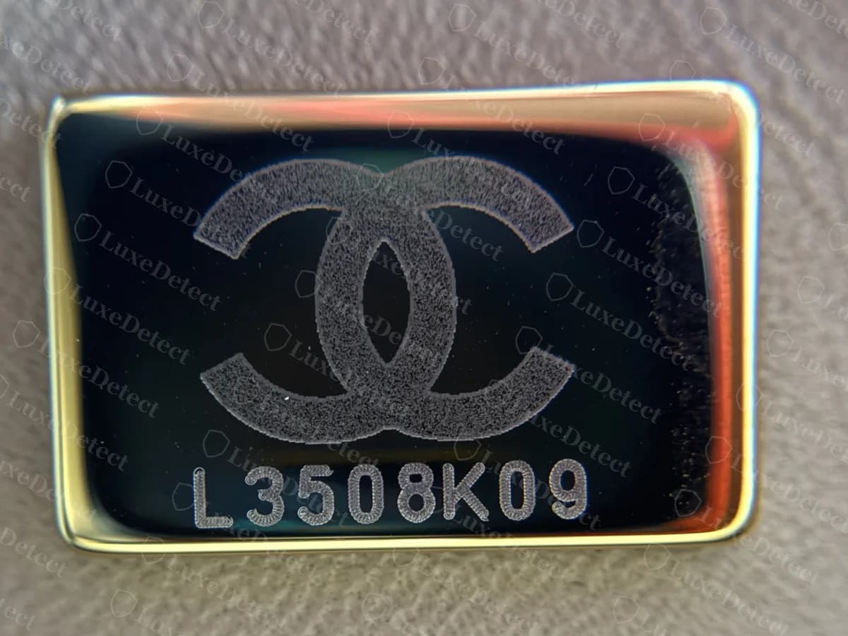 Placa de la era del chip original dentro de un Classic Flap: un logo CC grabado encima del código L3508K09 en una placa oscura con borde dorado