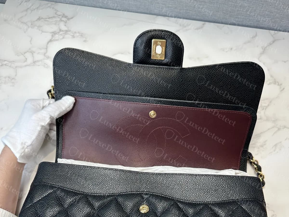 Classic Flap jumbo original de piel caviar negra abierto, con el interior burdeos, el bolsillo de la solapa con una CC cosida y la segunda solapa detrás