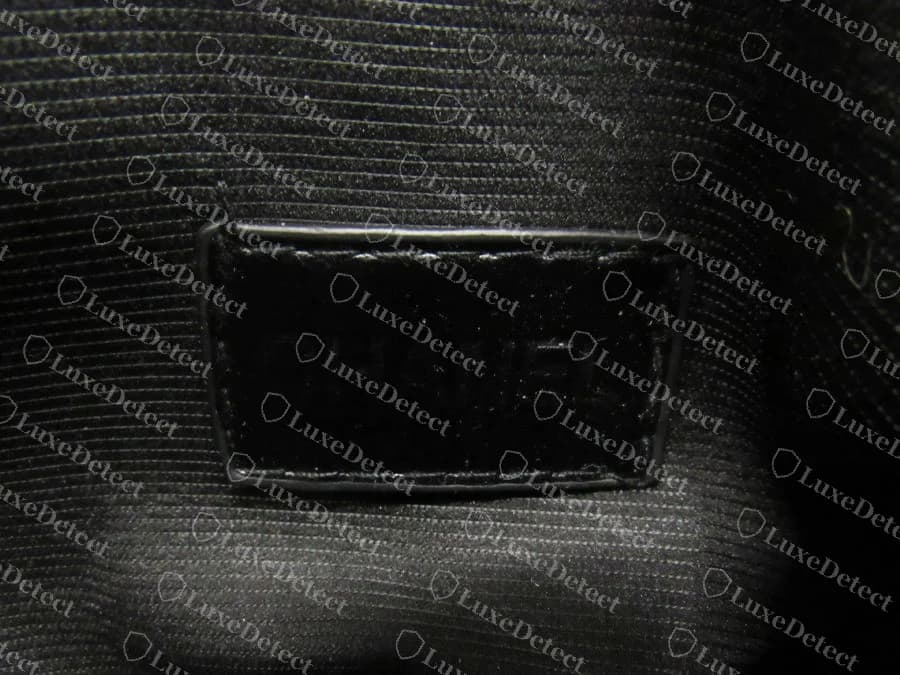 Counterfeit Chanel Deauville interior tag with smudged, bled lettering where individual letterforms are no longer distinct