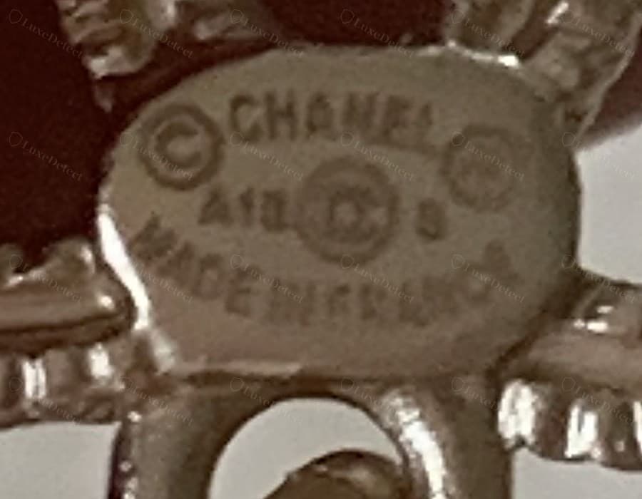 Punzone di un orecchino Chanel contraffatto: stessa disposizione e stessi simboli, ma il colpo è più superficiale e morbido, con “MADE IN FRANCE” che si fonde anziché leggersi come lettere separate e nitide