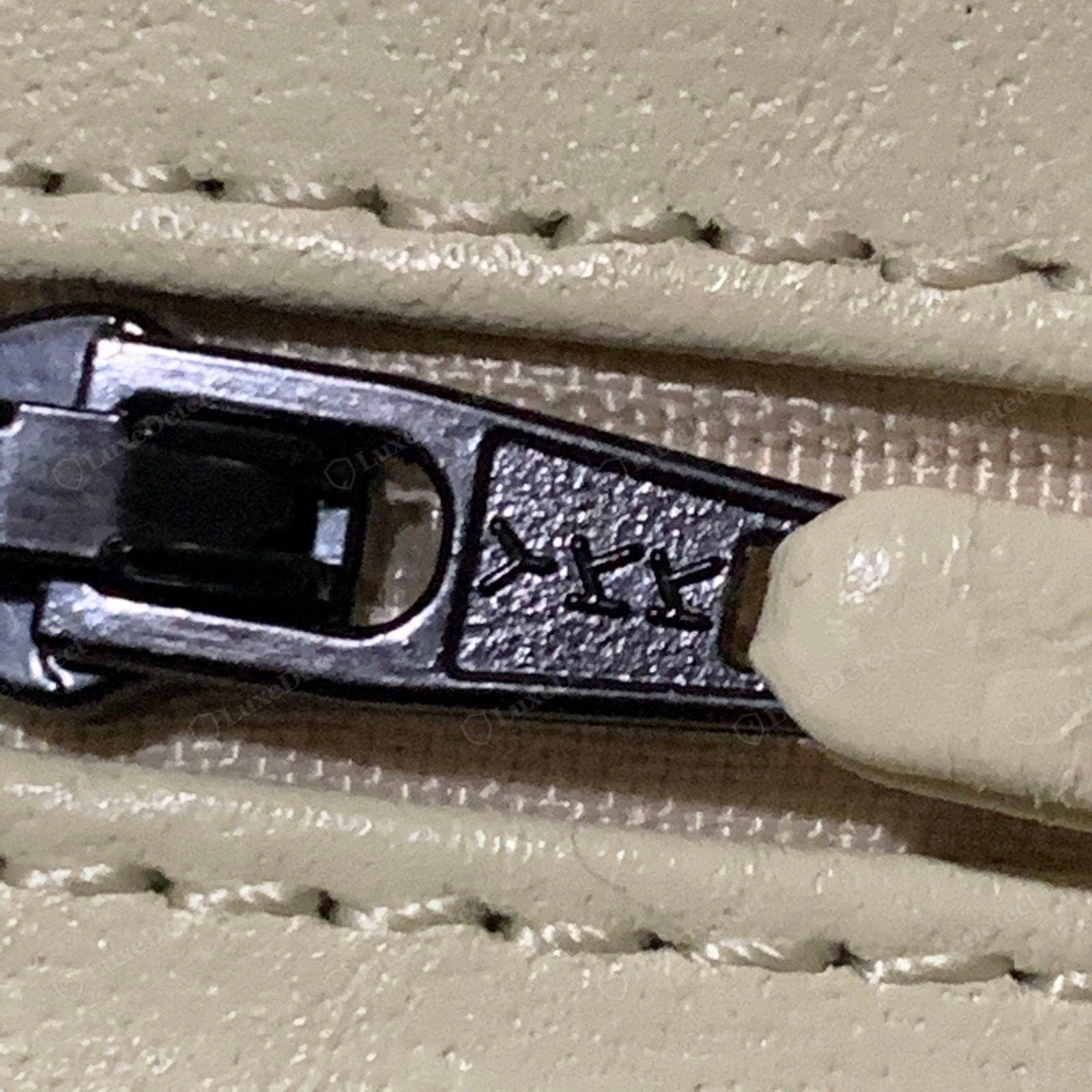 Counterfeit Chanel zipper — an unbranded slider or a "YKK" mark on a modern Classic Flap, a gritty action, a soft pull stamp