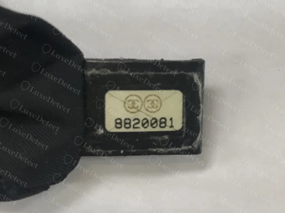 Echter Chanel-Seriennummern-Sticker mit siebenstelliger Nummer: 8820081 mit zwei CC-Kreisen, auf einem kleinen dunklen Streifen in einer Nylon-Tote