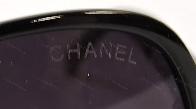 Gravure de verre Chanel contrefaite — la marque « CHANEL » gravée pâle et rayée, les traits des lettres se désagrégeant et l'épaisseur des caractères variant sur le mot