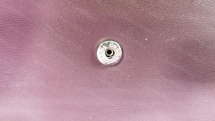 Counterfeit Chanel wallet snap closure — CHANEL CHANEL text embossed around the rim, a plausible but non-standard layout
