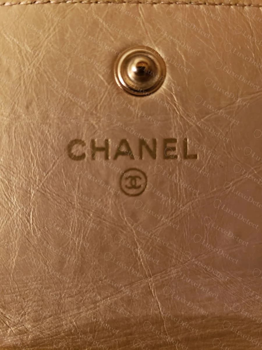 Authentic Chanel wallet snap closure — brass-toned hardware stamped CHANEL and CC, evenly finished with a slightly domed profile