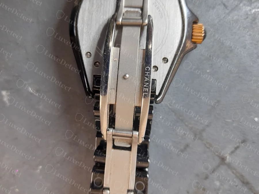Bracelet clasp hardware from a confirmed fake, stamped "CHANEL" but mounted to a case shape that doesn't match either the J12 or the Première