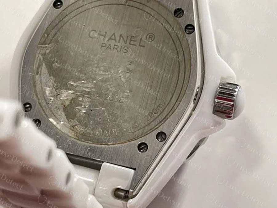 A fake J12 caseback with worn, partly illegible text and an odd unit-like fragment where a depth rating belongs, a garbled version of the format above rather than a clean copy of it.
