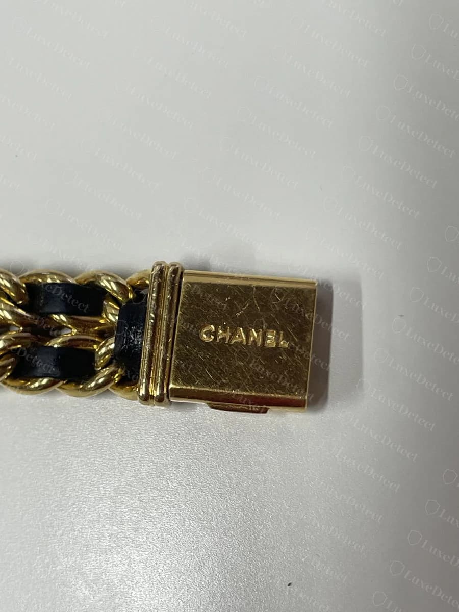 An authentic Première: octagonal gold case, "CHANEL" and "SWISS" printed on the black dial, gold curb-link bracelet woven with black leather.