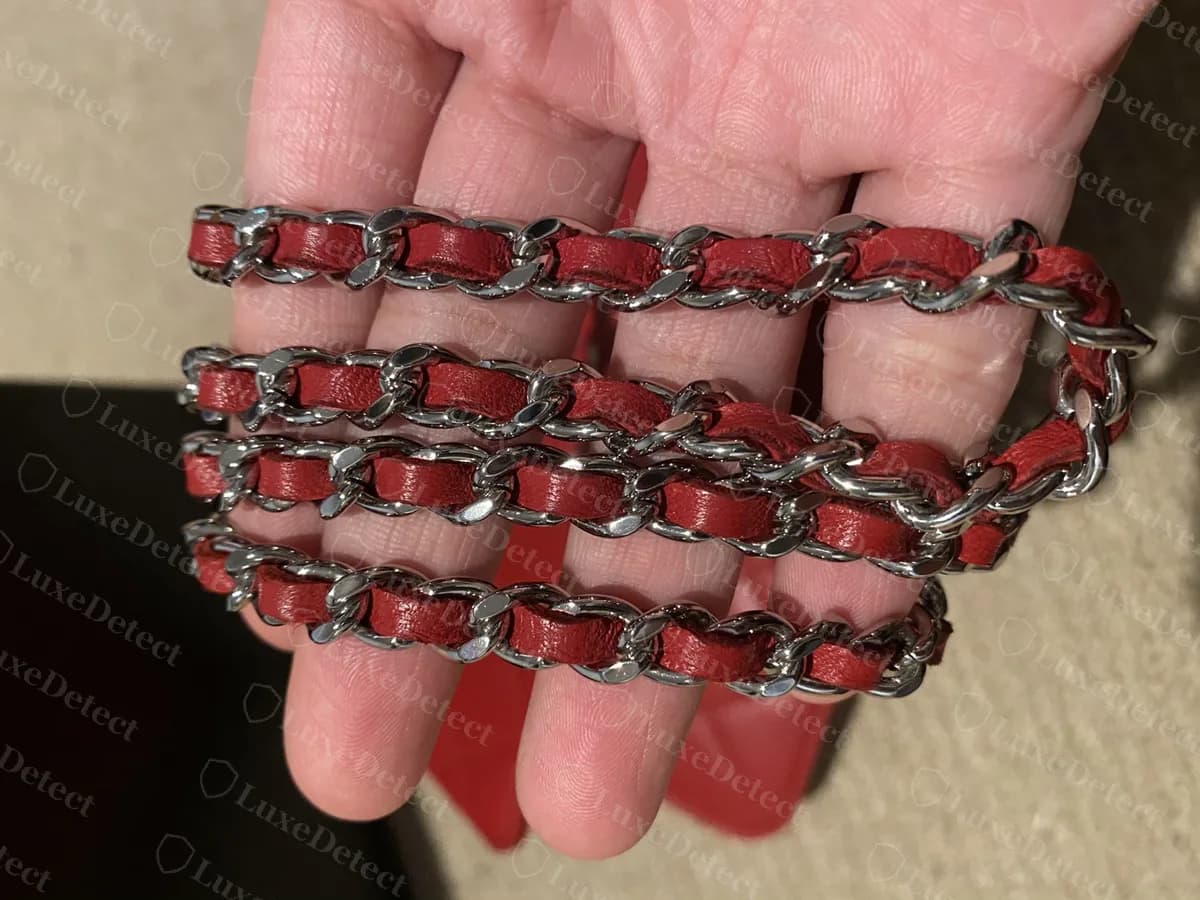 Genuine Chanel WOC chain: silver-tone links with red leather laced through them, held in a hand