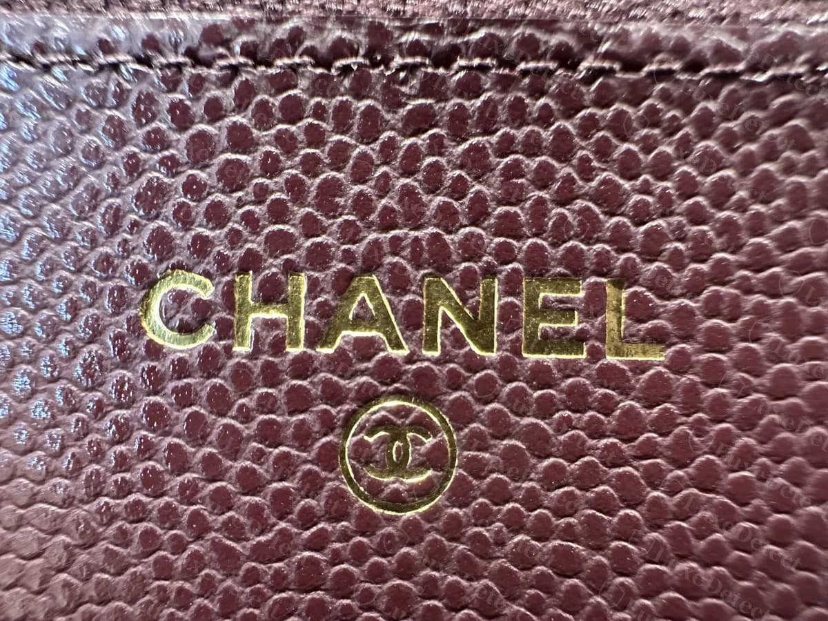 Genuine Chanel WOC interior stamp in gold foil on burgundy caviar: the word CHANEL in capitals above a circled CC
